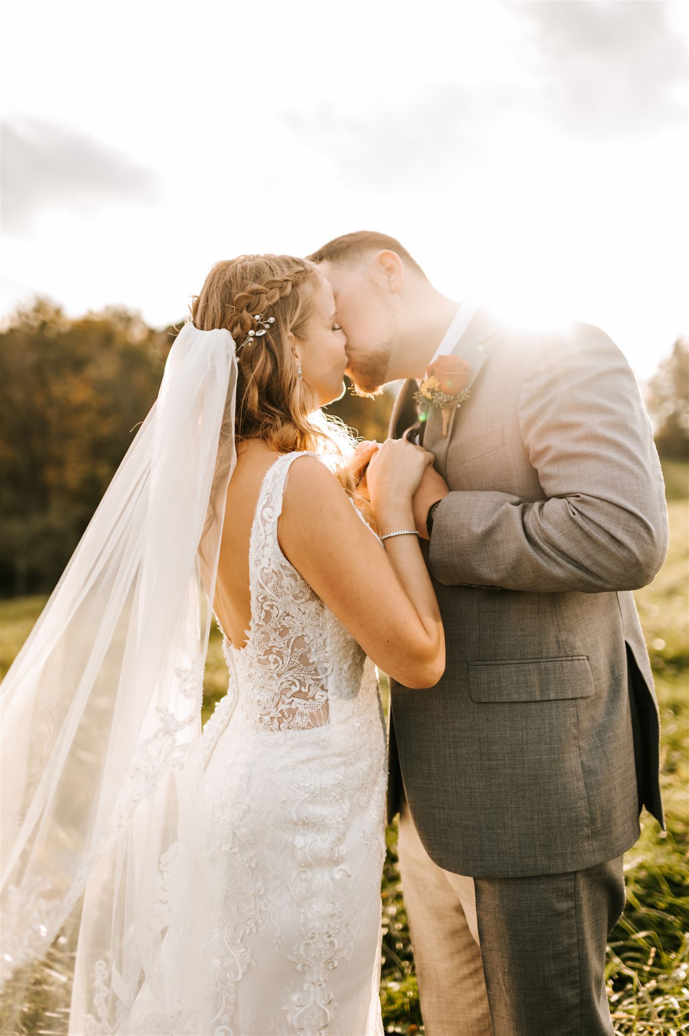 sunset wedding pictures with bride and groom kissing as the sun sets behind them and they hold their hands together close to their chests with Charlottesville Wedding Photographers