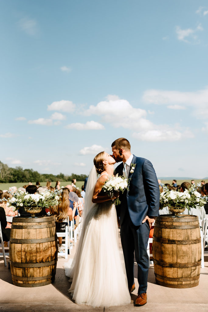 Charlottesville wedding photographer captures bride and groom exiting their outdoor Shenandoah wedding and kissing at the end of the aisle 