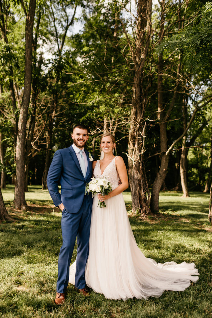 bride and groom standing together in the woods and smiling for their wedding portraits with Charlottesville wedding photographer 