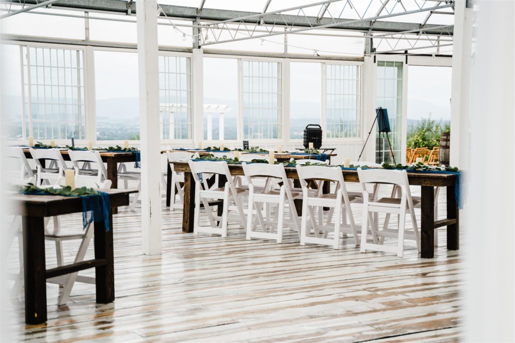 Shenandoah Valley wedding venues with indoor reception space in a greenhouse wedding with white tables and chairs and blue details in the wedding decor photographed by Virginia wedding photographer 