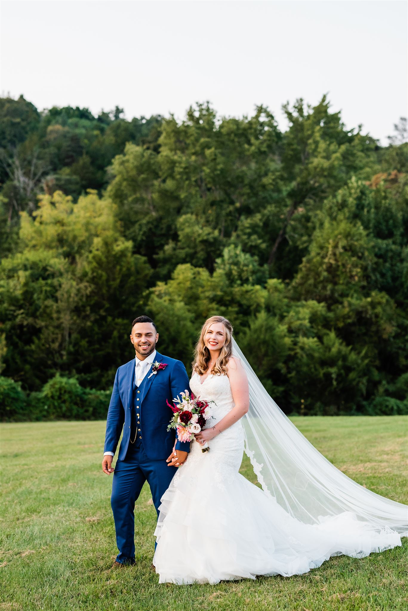 bride and groom holding hands and walking up a hill together in Shenandoah National Park with lush trees and mountains behind them captured by Charlottesville wedding photographer 