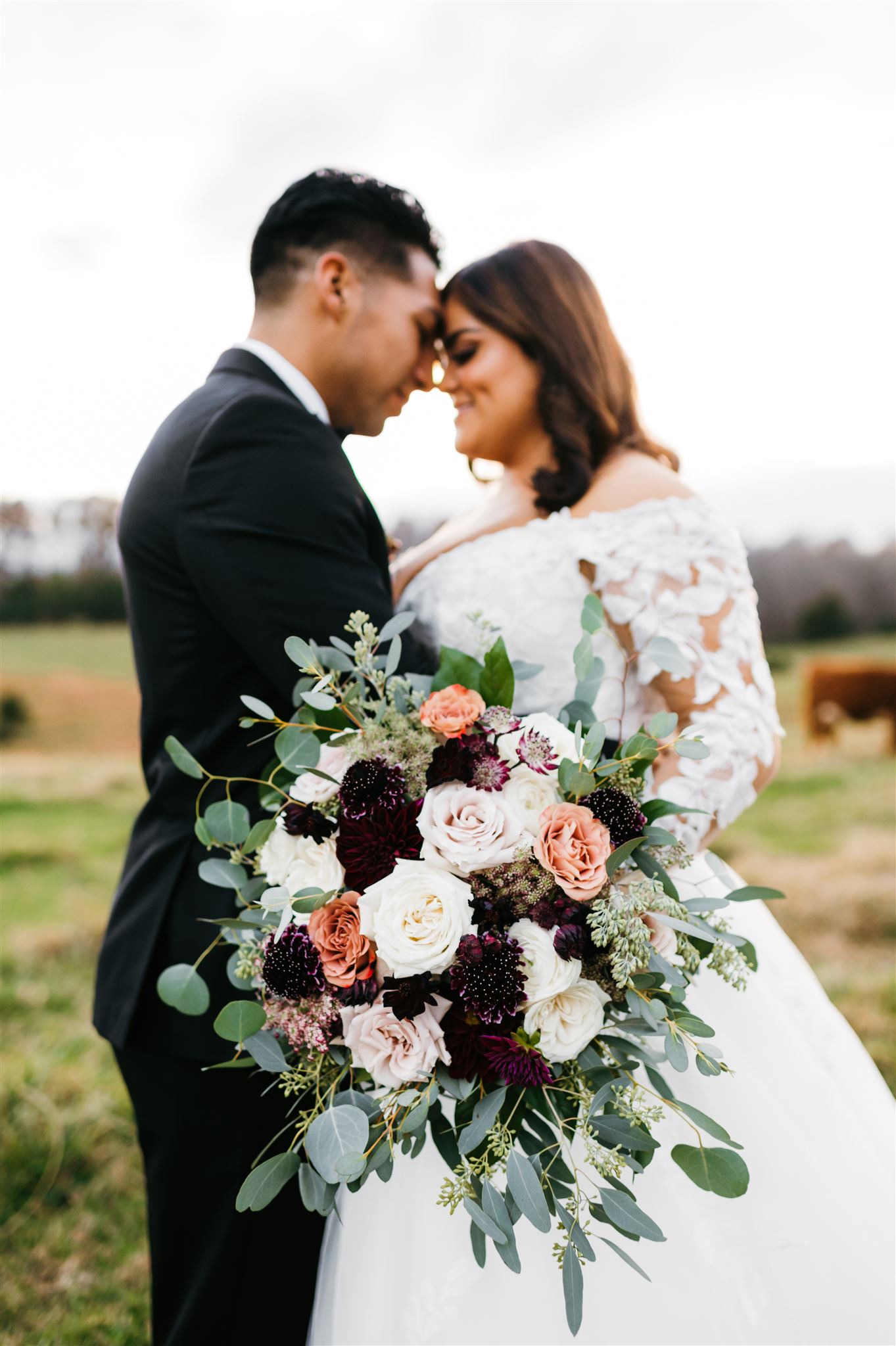 bride and groom embracing each other during their Shenandoah National Park Wedding pictures with Charlottesville wedding photographer with bride and groom holding their foreheads together and smiling with the bridal florals in hand