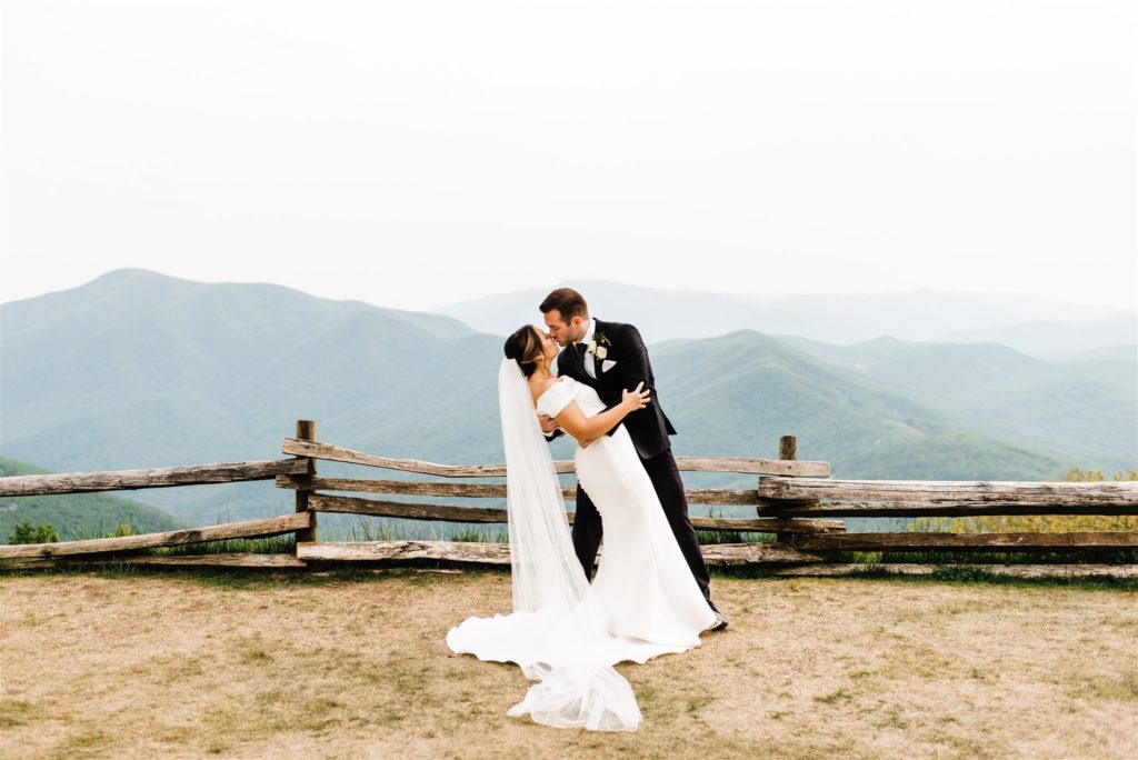 groom dips his bride backwards and passionately kisses her on a mountain top for their Shenandoah National Park Wedding
