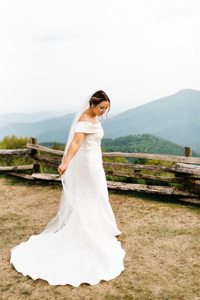 bride holding her veil and looks down as she poses for bridal portraits with Shenandoah National Park Wedding photographers