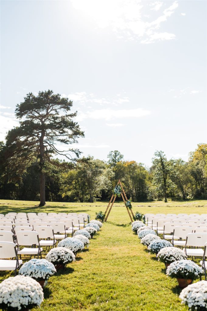 outdoor wedding venue in Shenandoah wedding venue with large white mums lining the aisle that approaches the wedding arch