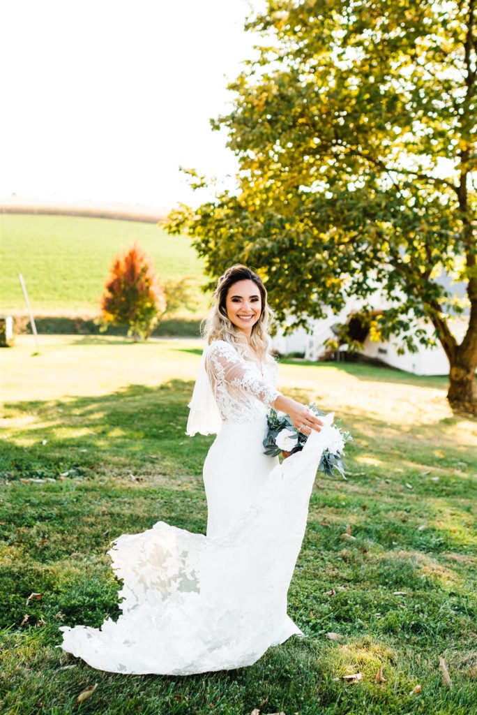 Shenandoah wedding portraits with bride wearing a lace wedding dress twirling in a field as she holds a floral bouquet captured by Charlottesville wedding photogrpaher