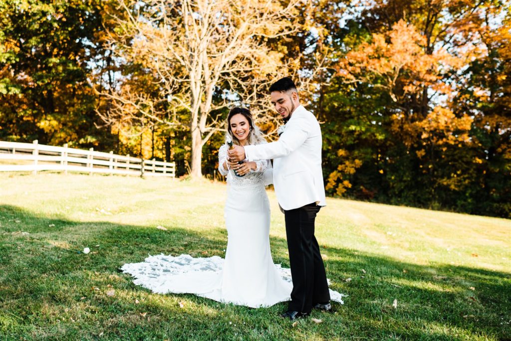 Charlottesville wedding photographer captures bride and groom popping champagne for their Shenandoah wedding in Virginia wedding venue in the fall 