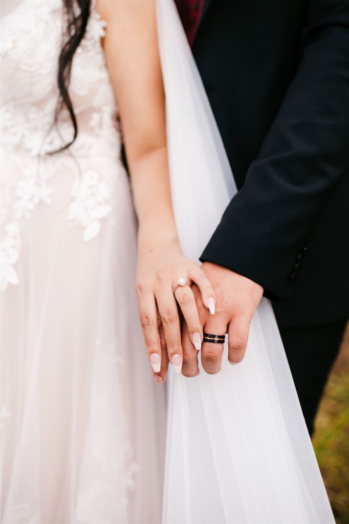 bride and groom holding hands together at their sides while showing off their wedding bands for their Shenandoah wedding with Charlottesville wedding photographer 
