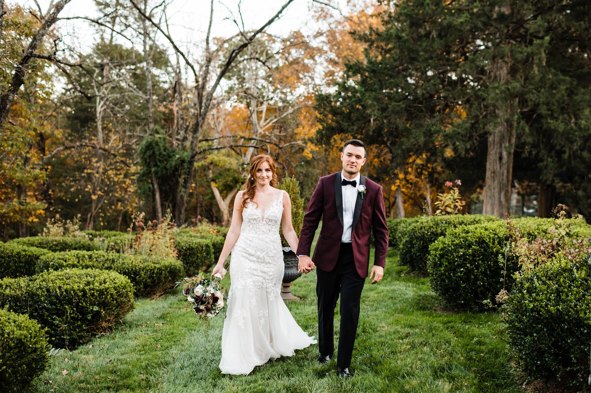 bride and groom holding hands and walking through a garden at their northern virginia wedding venue and smiling captured by northern Virginia wedding photographer