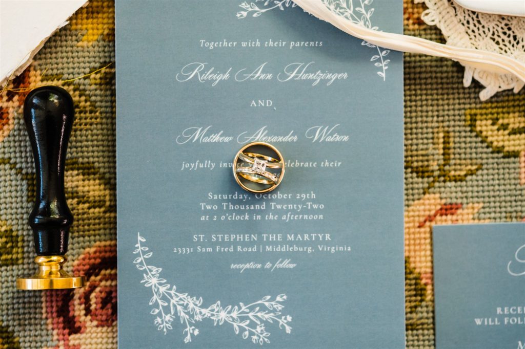 wedding rings and engagement ring sitting together on a wedding invitation for flatlay photos for Shenandoah wedding 