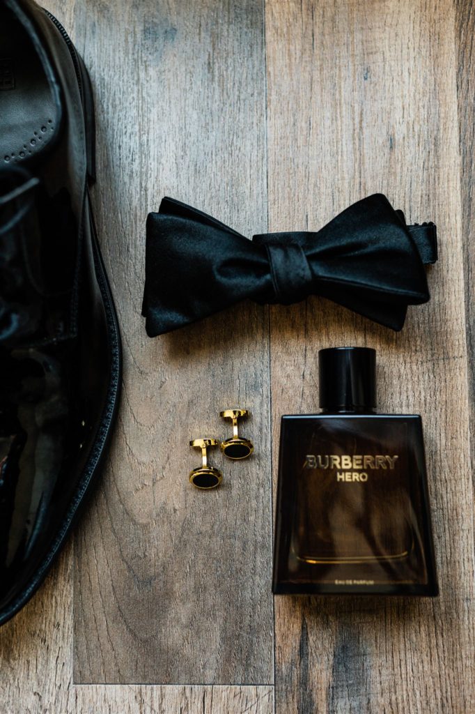 Charlottesville wedding photographer captures grooms details in a flatlay with his bowtie, cologne, and shoes 