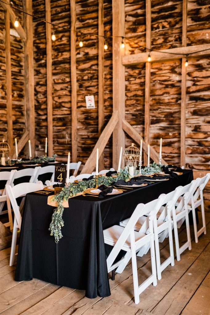 Shenandoah Valley wedding venues indoor barn reception space with white chairs and greenery decorating the space captured by Virginia wedding photographer