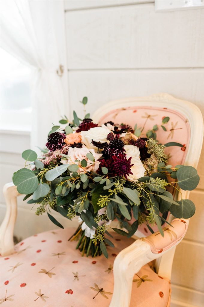 brides wedding bouquet sitting on a pink chair in a bridal suite for her Shenadoah wedding captured by Charlottesville wedding photographer