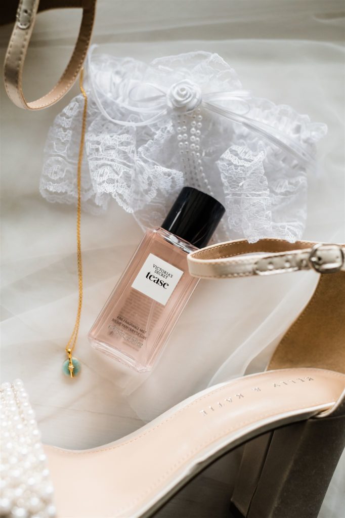 Shenandoah wedding with brides perfume and shoes sitting together on a white surface captured by Charlottesville wedding photographer
