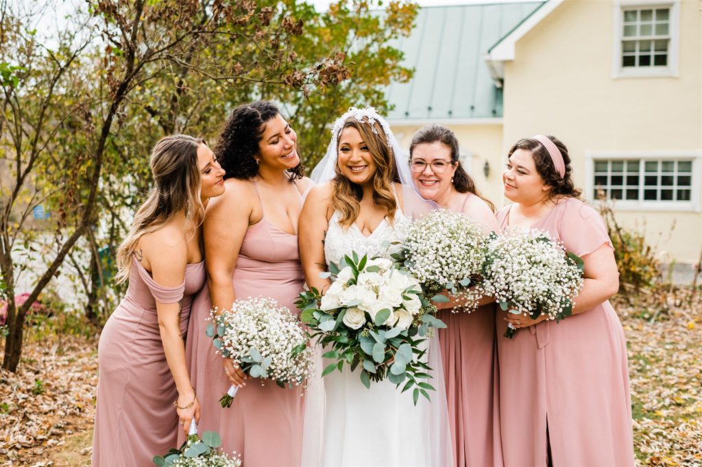 bride holding a white rose bouquet while standing with her bridesmaids for her outdoor Shenandoah wedding captured by Charlottesville wedding photographer 