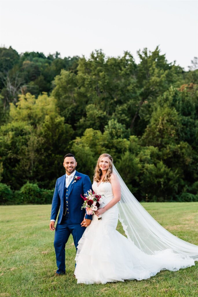 bride and groom holding hands and walking up a hill at their Shenandoah valley wedding venues with a tree line of evergreens in the distance captured by Virginia wedding photographer