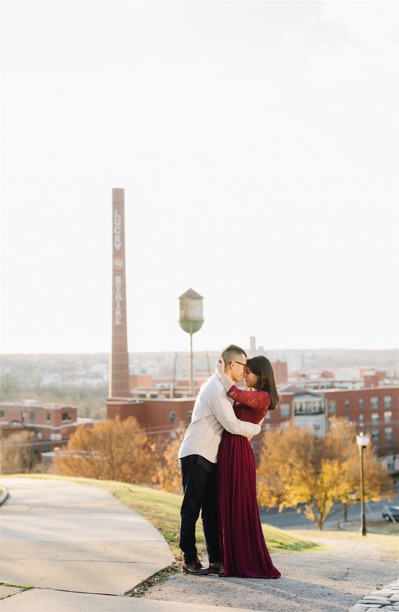 Richmond engagement photos with couple embracing on a hilltop at Libby Hill Park with the view of the city down below at sunset