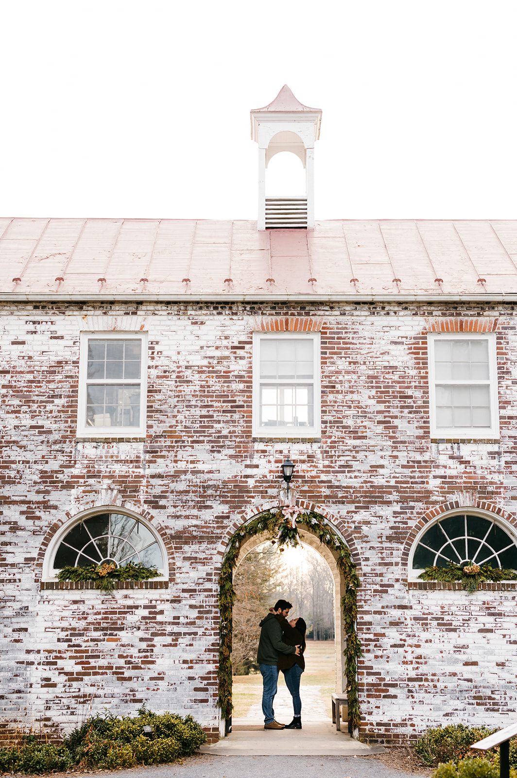 State Arboretum of Virginia engagement photos with couple embracing under and arch in the courtyard's brick building