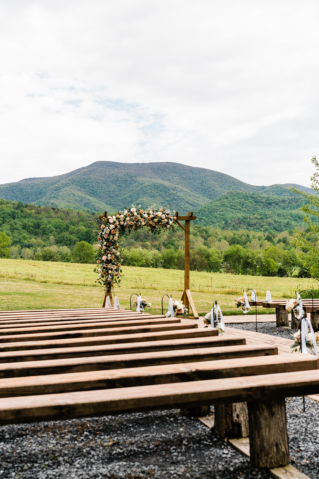 Charlottesville wedding photographer captures outdoor ceremony spot with rose florals decorating the wedding arch and aisle at Shenandoah National Park wedding