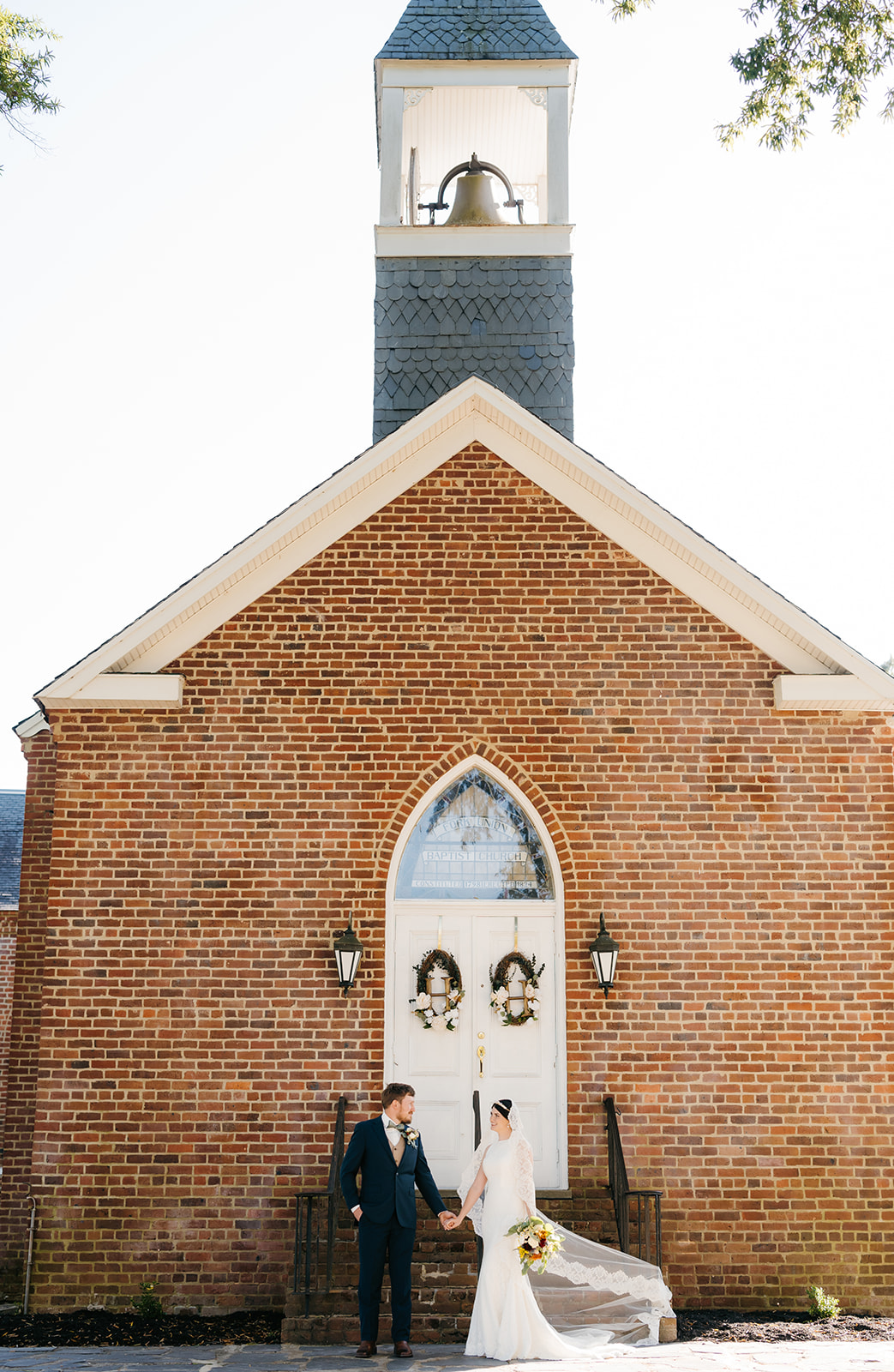 Charlottesville wedding chapel photos with bride and groom holding hands and facing each other right outside of the chapel stairs for wedding photos by Charlottesville wedding photographer