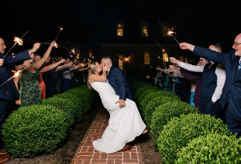 Groom and Bride kissing sparkler exit in front of the Manor House Seven Springs, Va