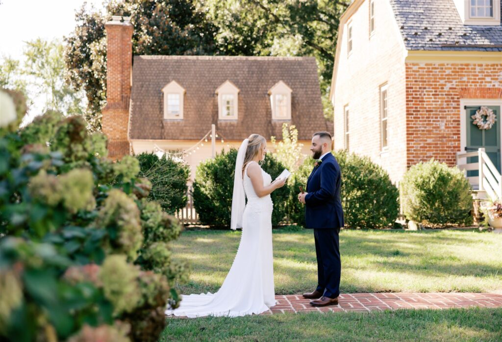 Zoey and Brandon reading their private vows during first look in front of the Manor House at Seven Springs.